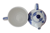 Ceramic teapot and cup with blue floral patterns on a wooden surface